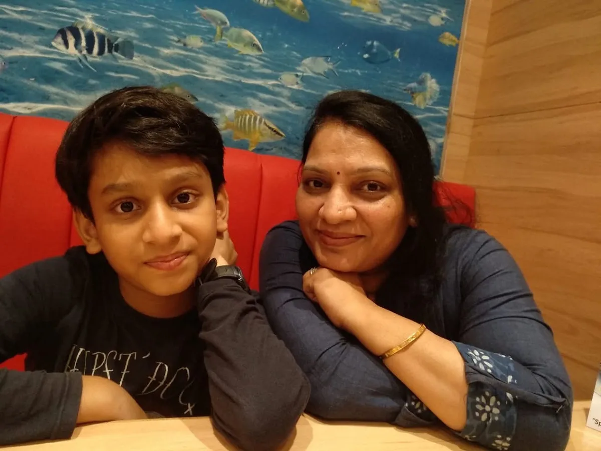 The founder as a boy, sitting beside his mother in a restaurant booth, both smiling at the camera.